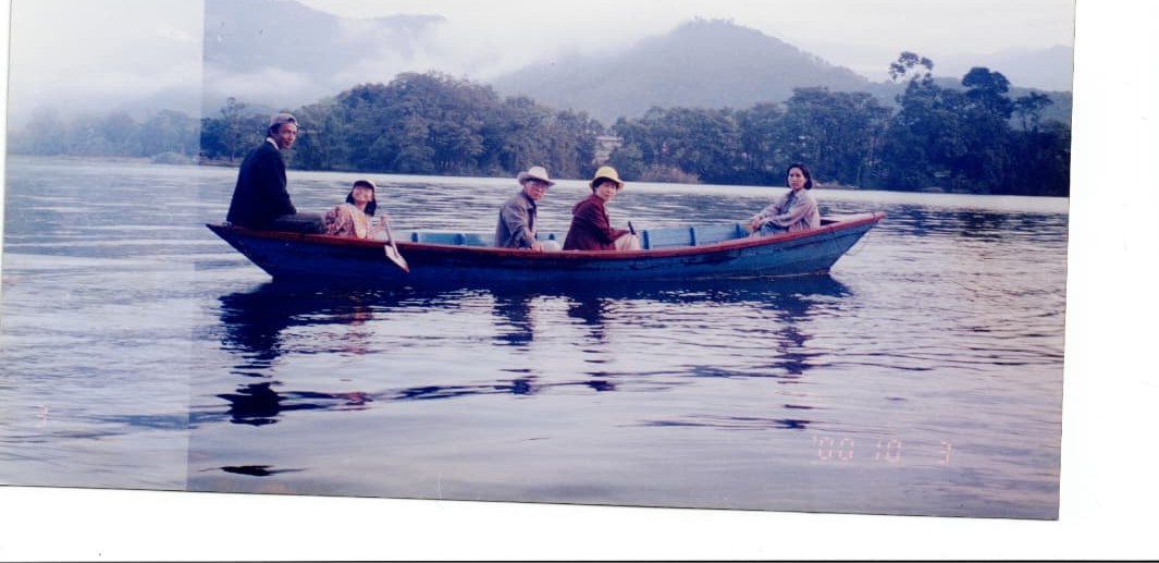 Haena as a child with her family in a wooden boat on a misty lake
